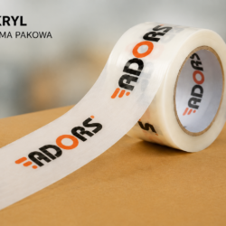 Taśma pakowa akrylowa z nadrukiem ADORS na tle kartonu. Taśma z klejem akrylowym przeznaczona do zaklejania paczek i przesyłek.